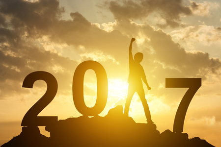 Man hand up on the peak of mountain and sunlight  with text 2017 happy new year calendar holiday conceptの写真素材