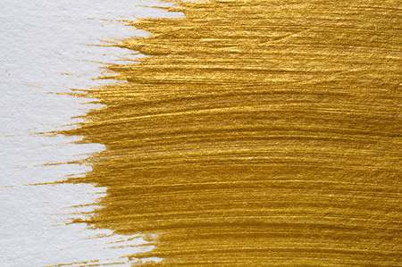 Gold acrylic paint on white paper background , gold texture free hand stoke object paintの写真素材
