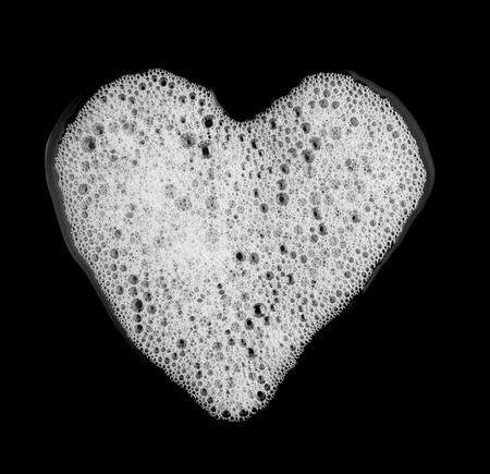 Bubble foam of soap shampoo heart shape isolated on black background top view object health conceptの写真素材