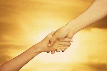 Helping hand of man and women on sunset background , team work help hope religion conceptの写真素材