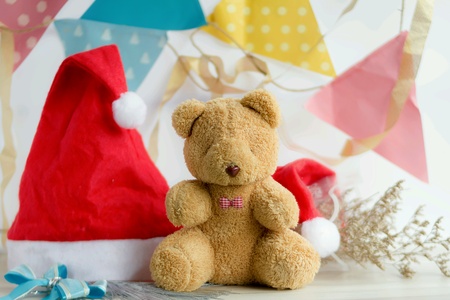 Teddy bear gift, on wood table, with Santa claus red had, flowers, pastel flags, happy new years conc.の素材