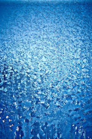 Background a texture. A winter window become covered by patterns from blue iceの写真素材