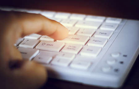 Close-up of finger. Businessman pointing at Enter button on computer keyboardの写真素材