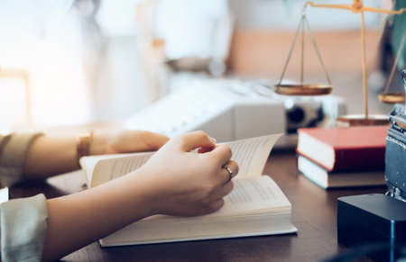Female lawyer reading legal books while she working on deskの写真素材