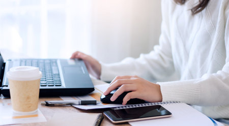 Close-up of young businesswoman using laptop and smartphone working online at home, Concept work...