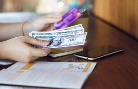 Closeup of girl hand holding hundred dollar and credit card.  Concept you can  payment or withdraw using a credit card.の写真素材