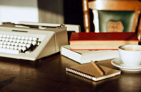 Place of work on wooden desk have old typewriter, note, book and coffee with sunlight in the morning. Retro styleの写真素材