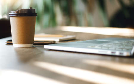Place of work on wooden desk with laptop, cup of coffee, notebook and mobile phoneの写真素材