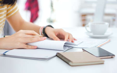 Young female reading information in notebook and working with paperwork on deskの写真素材
