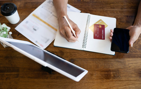 Male hand calculating his monthly expenses with credit card,smart phone and digital tablet, concept...