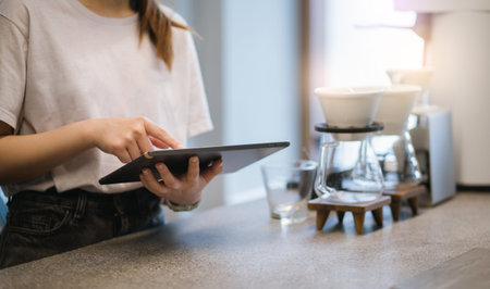 Close-up young asian woman holding and use digital tablet to receive orders from customers in coffee shopの写真素材