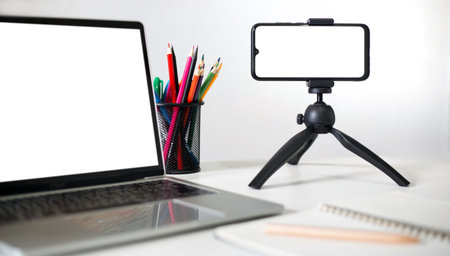 Mobile phone on small tripod with computer laptop on table use for live streming or video call