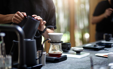 Barista pouring hot water through a coffee filter into the coffee glass on count bar in cafeの写真素材