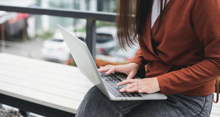 Focus on hand young asian woman typing on computer laptop while she working online outdoorの写真素材