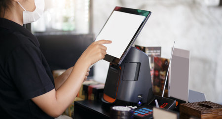 Close-up of young asian woman wearing face mask touching on the digital tablet to recive order from...