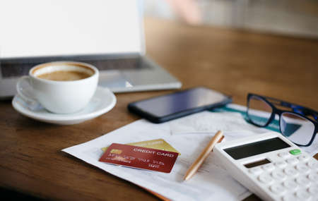 Focus on mock up credit card on bank statement with calculator, mobile phone and laptop on deskの写真素材