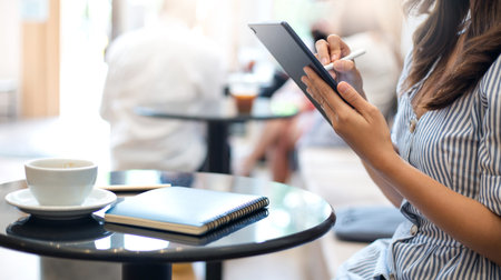 Young asian woman in casual clothes is working and chatting on digital tablet with friend while...