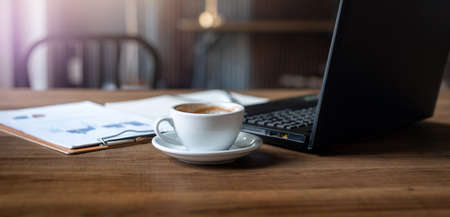 Cropped shot place of work on wooden table have coffee drink, laptop, paperwork  of investment, Concept work from homeの写真素材