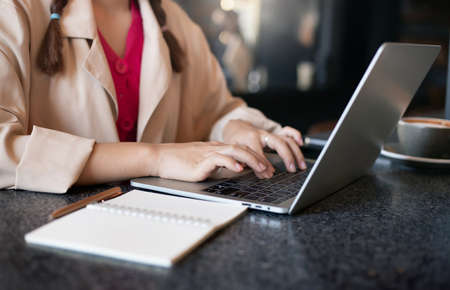 Young asian woman in casual cloth using laptop computer working or study online. Closeup photo and select focus on handの写真素材