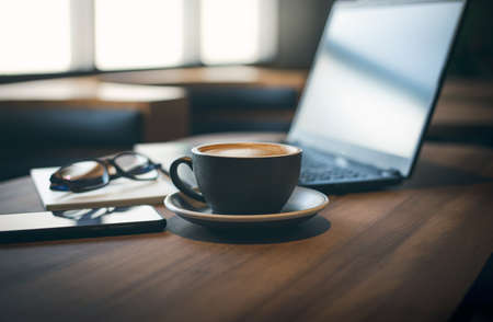 Work from home, desk office with laptop, blank notepad, eye glasses, mobile phone and coffee cup on wood tableの写真素材