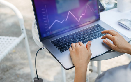 Young asian businesswoman analyzing statistics on laptop screen, working with financial graphs...