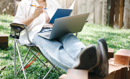 Casual asian woman sitting on folding chair she looking her job in book and working part time with...