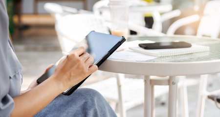 Young asian woman sitting in outdoor cafe and using tablet computer working part time or shopping...