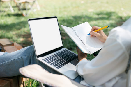 Casual asian woman sitting on folding chair she looking and writing her job in book and working part...