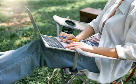 Young asian woman in casual clothes using computer laptop working online outdoor, female investor use laptop to trading stock and shopping or paying onlineの写真素材