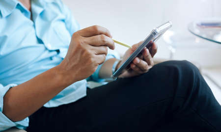Close up view. asian businessman using stylus pen with mobile phone to working and find information about investments and trading stocks, cryptoの写真素材