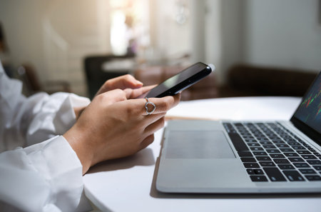 Young asian businesswoman using mobile phone to find information for investment analysis for trading...