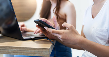 Two of young asian woman working on laptop and using mobile phone to searching data for her new...
