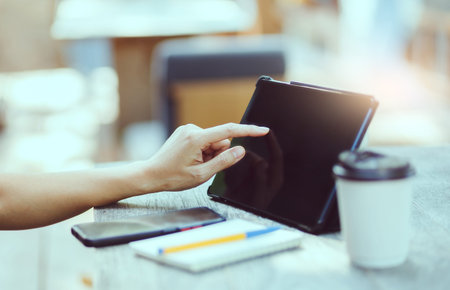 Asian freelance woman working and meeting on tablet computer on wooden table at outdoor cafe....