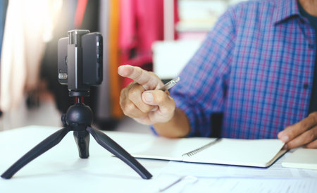 Asian man in casual clothes working at home to start new business and talk to customers online via...