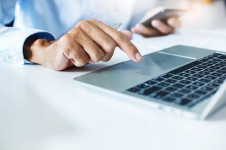 Hand man using laptop computer contact business search information on desk at home office checks...