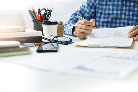 Asian businessman reviewing document reports at office workplace, legal expert, professional lawyer reading and checking financial documents or insurance contract before signの写真素材