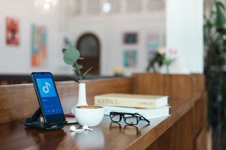 Coffee break after work listening music in mobile by wireless earphones with eyeglasses and reading...
