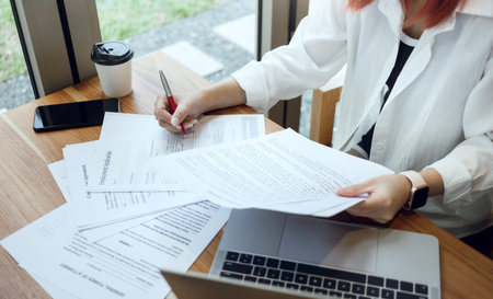 Young female or freelancer in casual clothes reading application form at table before filling in the...