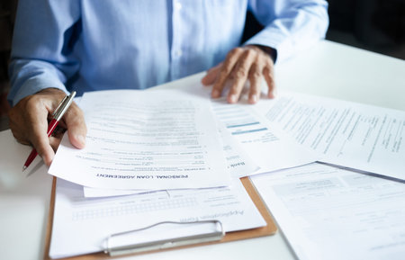Asian businessman reading personal loan agreement and review details of the contract In order to...