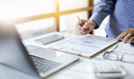 Businessman or lawyer holding pen checking financial report or business contract from documents...