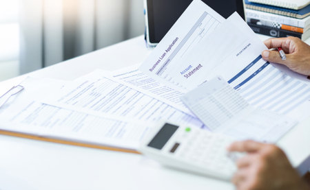 Asian man check business loan documents and bank statement. calculate income to apply for a loan to start new business SME. Concept start small business at home, Close-up shotの写真素材