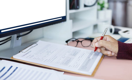 Hand of businessman holding pen working on desk with business documents and meeting online via computer, meeting and chat via desktop PC with business group to start new business planの写真素材