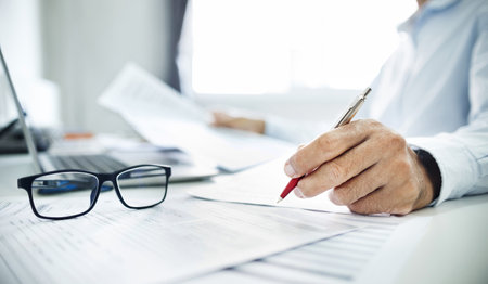 Close-up shot, businessman or lawyer holding pen reviewing documents and contact customer via laptop to give advice about business contracts and various important documents for start new businessの写真素材