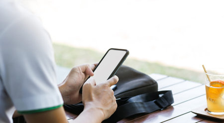 A man sitting outdoor relaxing and using smart phone