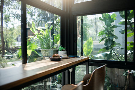 White coffee cup and chocolate cake with mobile and note book, small tree in vase on wooden counter in cafe for breakfast and outdoor garden backgroundの写真素材