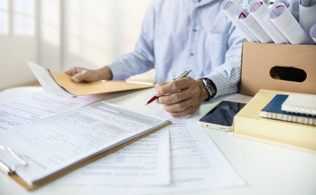 Businessman work hard in office with many ocuments,legal expert, professional lawyer reading and checking financial documents or insurance contract before signの写真素材