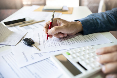 Men's hand holding pen checking personal loan contract and calculate monthly installments before sign contract to apply for a loan. concept to purchase the first carの写真素材