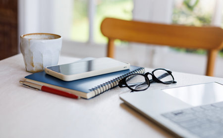 Comfortable workplace with laptop computer, mobile on note book, eyeglasses with coffee drink for...