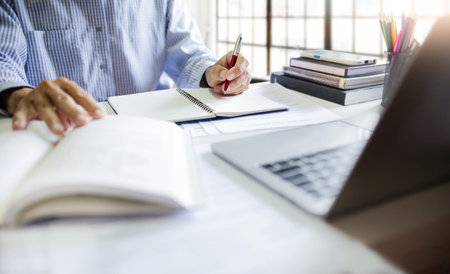 Asian businessman sit at desk work on laptop making notes. watch webinar or training course via...