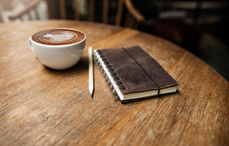 Latte coffee with pencil and old book on wooden table, Close-up shot, retro style